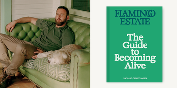 a person lounging on a green vintage couch with a dog next to a book titled the guide to becoming alive