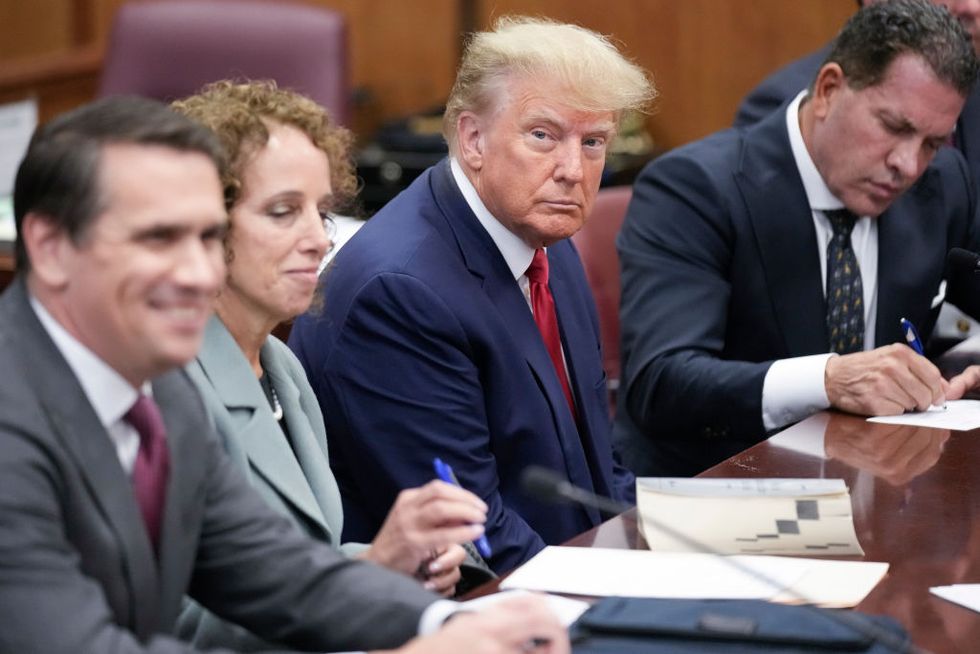 president donald trump sitting with his lawyers at a courtroom desk