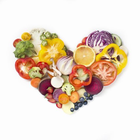 Flat lay conceptual vegan food in heart shape on white background.
