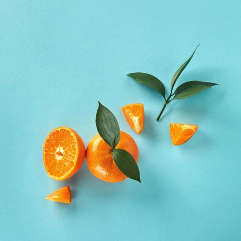 flat lay exotic citrus fruits with green leaves on a blue paper background