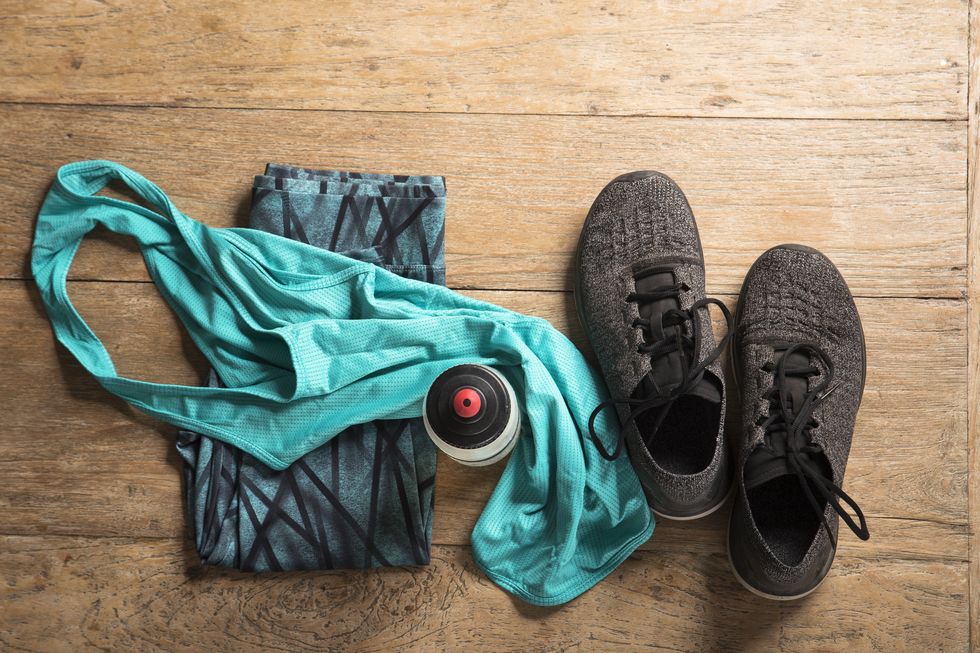 flat lay image of sports clothes and shoes on a wooden floor