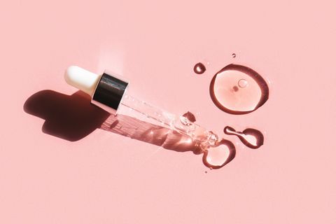 liquid gel or serum drop with pipette on pink background in macro