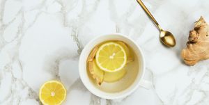 Flatlay of healthy drink with lemon and fresh ginger root on marble background, natural cold or sore throat