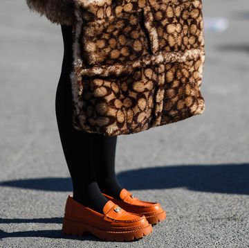 a person wearing a brown jacket and orange shoes