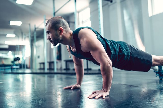 male athlete doing plank exercise in gym