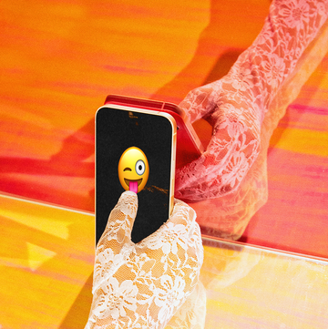a lace gloved hand holding a phone with a flirty emoji on the screen