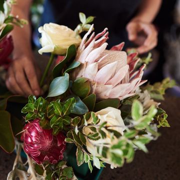 florist making a flower arrangement with proteas