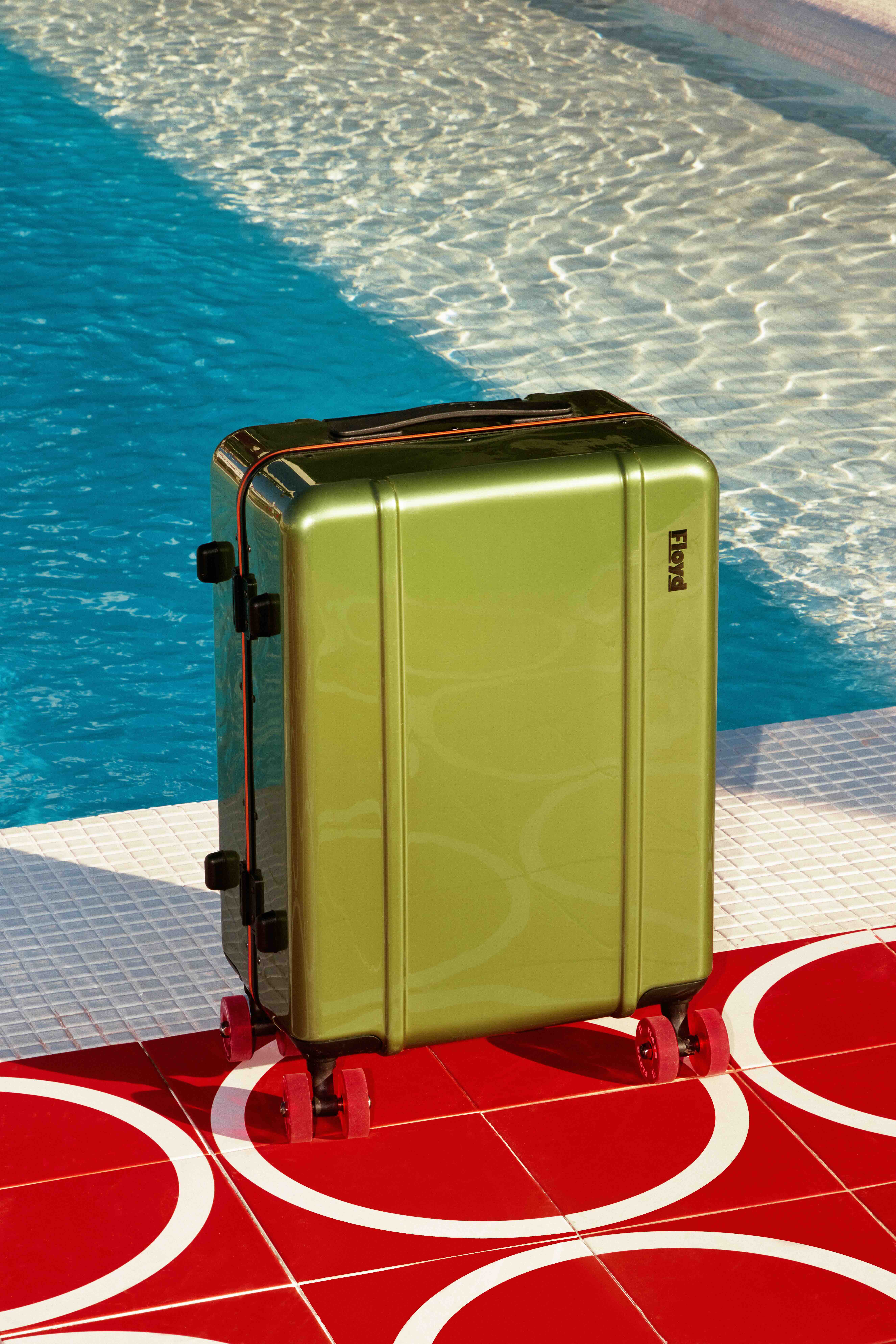a green suitcase by the pool