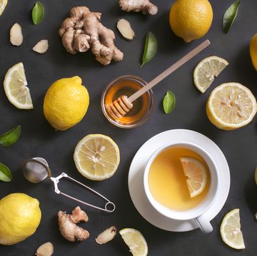 A cup of lemon ginger honey tea on rustic wooden background.
