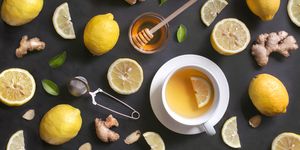 A cup of lemon ginger honey tea on rustic wooden background.