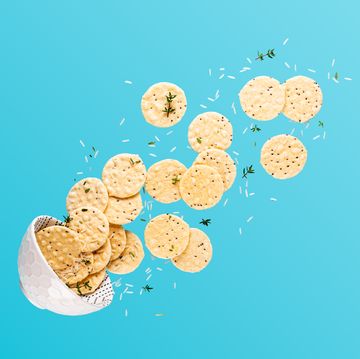 flying bowl with rice crackers, white rise and thyme branches over blue background levitation food composition with copy space
