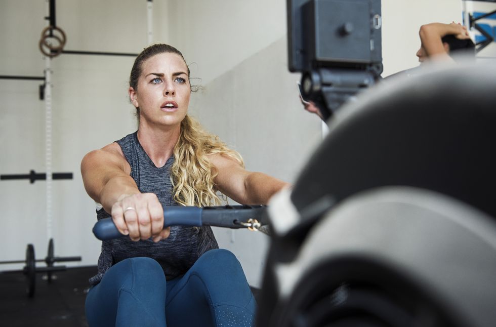 focused athlete exercising on rowing machine in gym gym