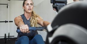 Focused athlete exercising on rowing machine in crossfit gym