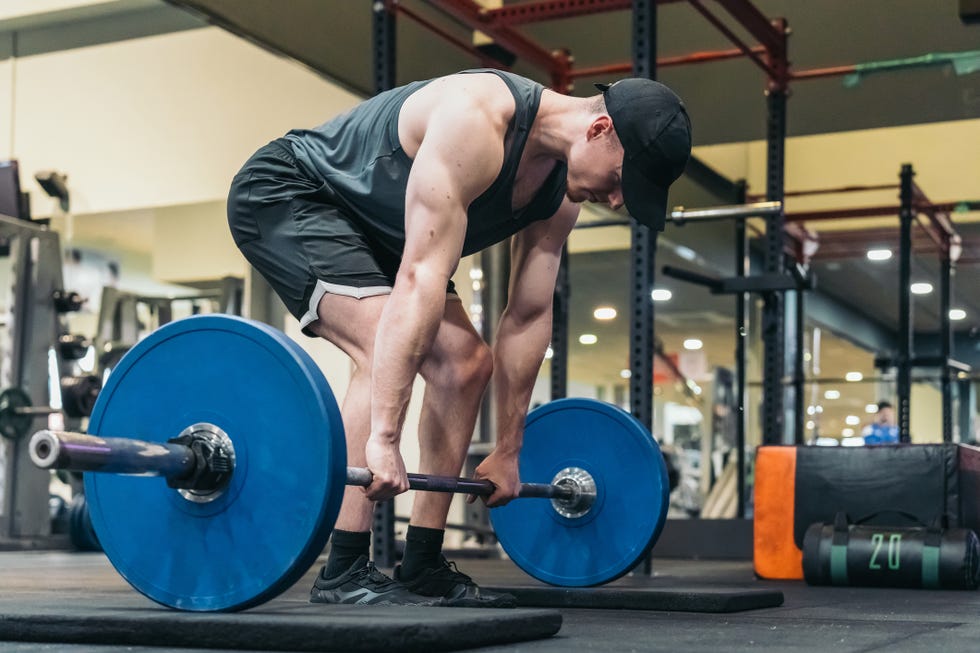 focused athlete in cap, ready to perform deadlift in gym