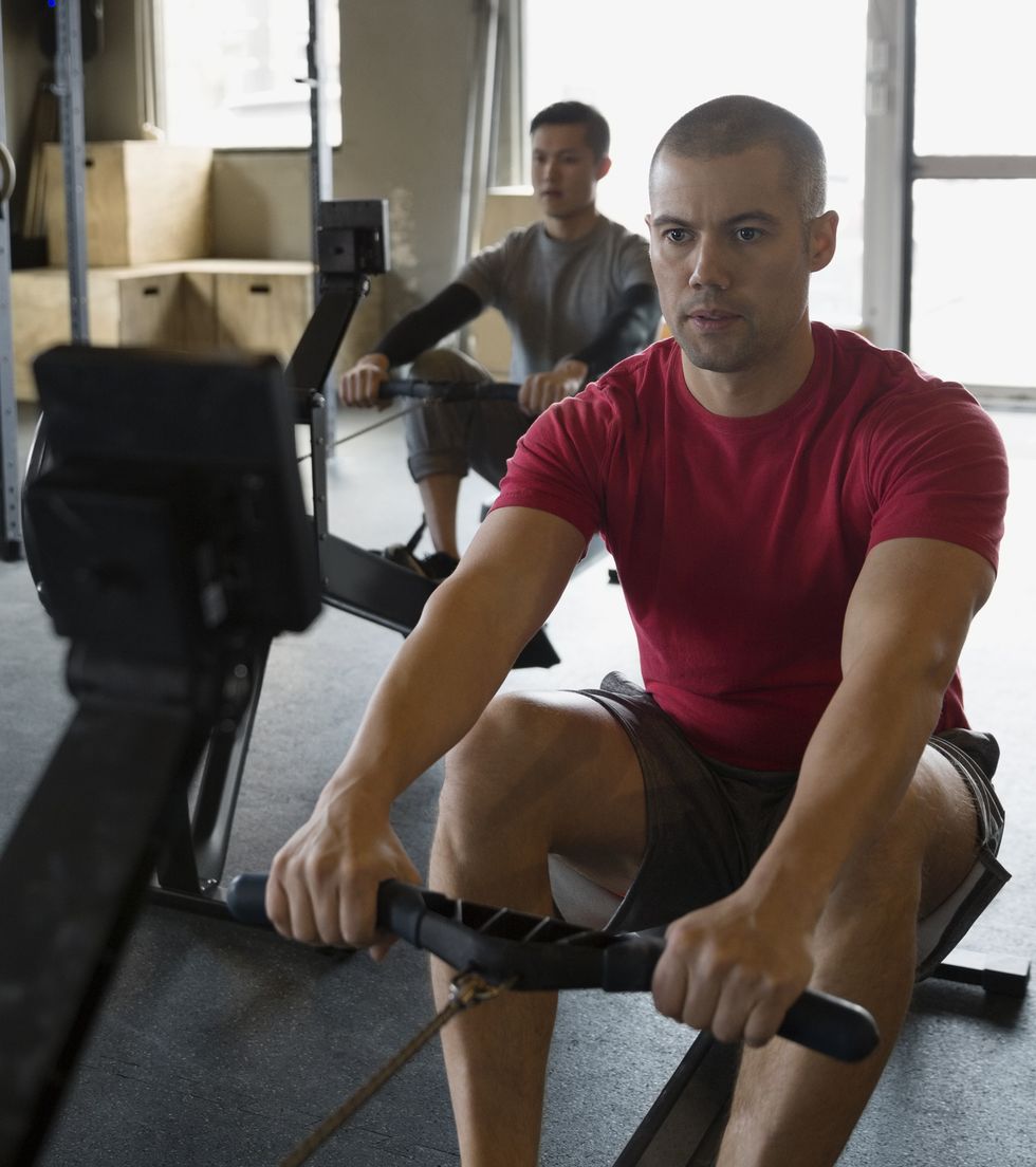Focused man using rowing machine at gym