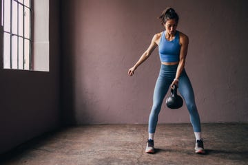 focused woman exercising with kettlebell in a gym setting