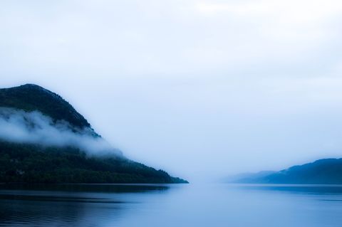 fog over lake among forest covered hills, highlands, scotland, uk