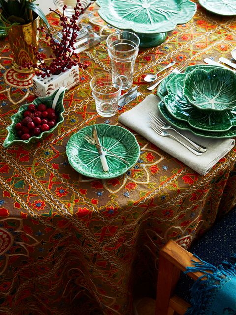 a table setting with a colorful orange and brown tablecloth and cabbage dinnerware