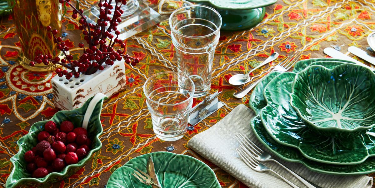 a table set with an orange and brown tablecloth cabbage ware and red accents