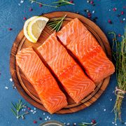 food background, sliced portions large salmon fillet steaks on chopping board on dark blue concrete table, copy space, top view