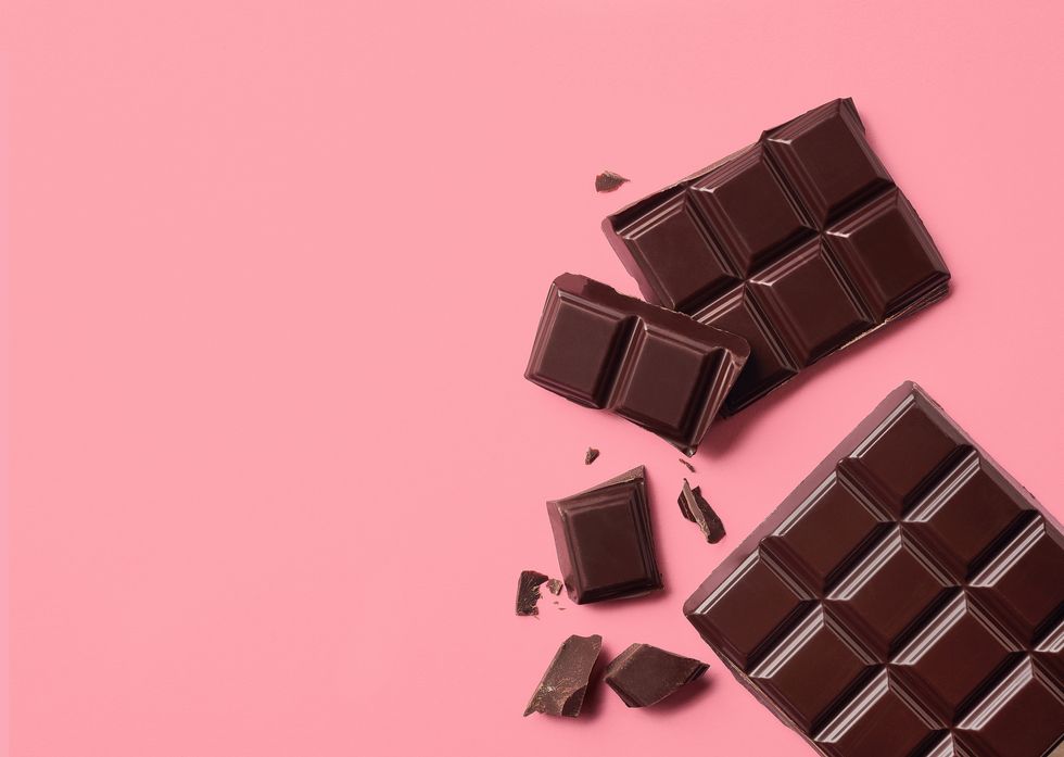 food for period pain dark chocolate on pink background top view