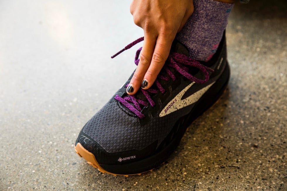 a person adjusting the laces of a running shoe