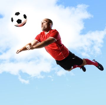 voetballer die in de lucht hangt om voetbal te koppen