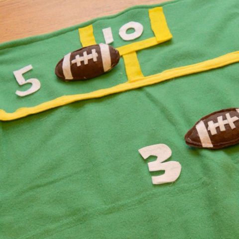 bean bag toss super bowl party game with a felt field on the floor and football shaped bean bags