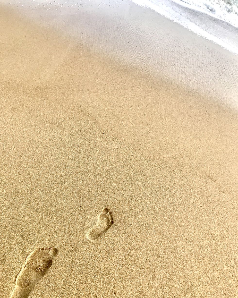 high angle view of footprints on sand at beach in front of surf