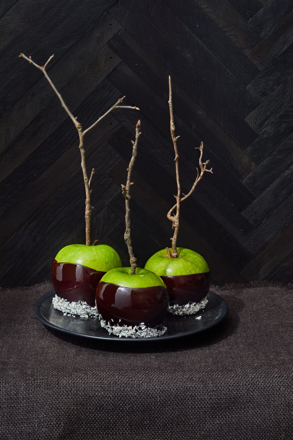 green apples dipped in dark brown candy coating with twigs attaches as the stem