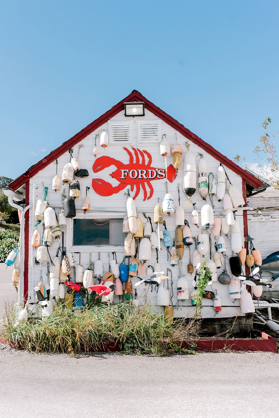 white exterior of fords lobster shack covered in colorful buoys