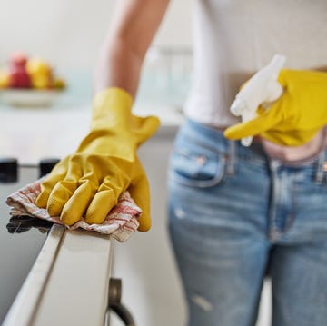 a woman cleaning a stovetop with spray and a rag