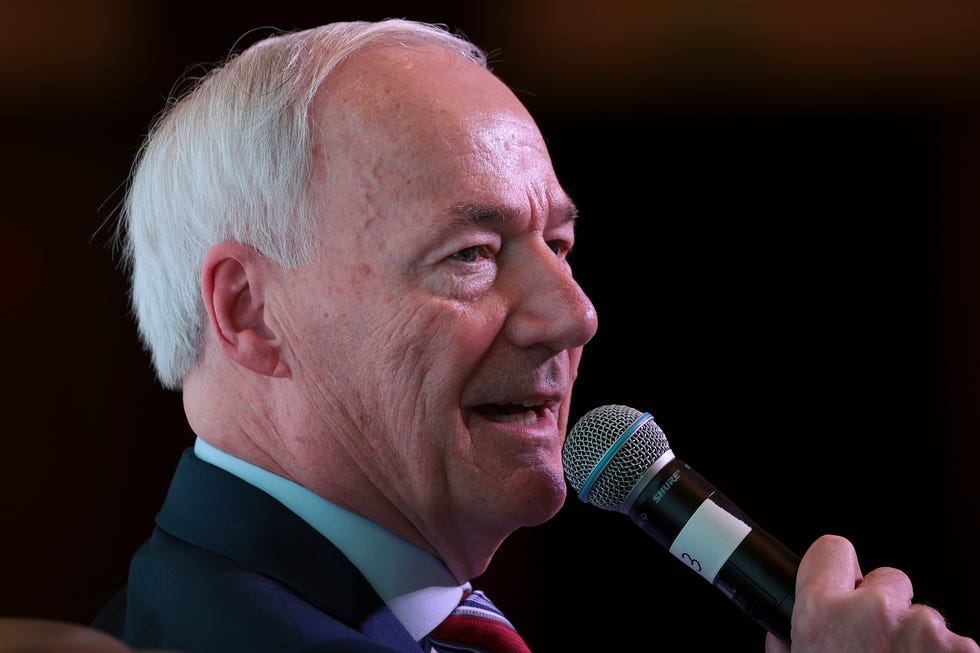 asa hutchinson holding a microphone as he talks to an audience