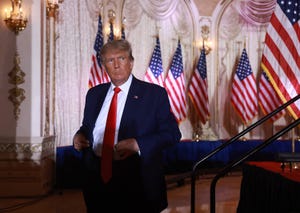 former president donald trump standing in front of american flags