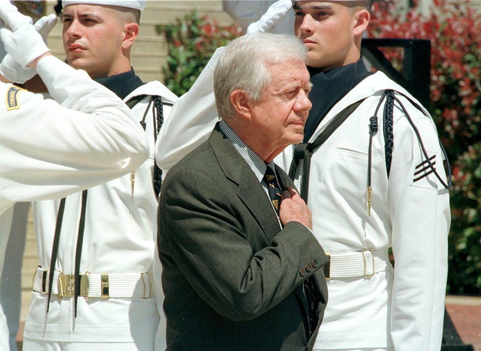 former president jimmy carter walks past a naval honor guard during a dedication ceremony for a nuclear submarine bearing his name at the pentagon april 27, 1998 in washington, dc