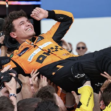 formula 1 driver lando norris celebrates his first win as he's lifted into the air by his mechanics and engineers in the pit lane