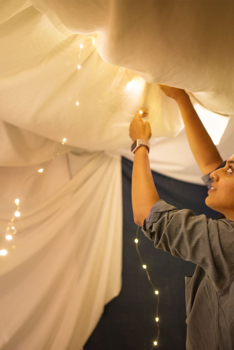 shot of a couple adding lights to a tent made in their living room
