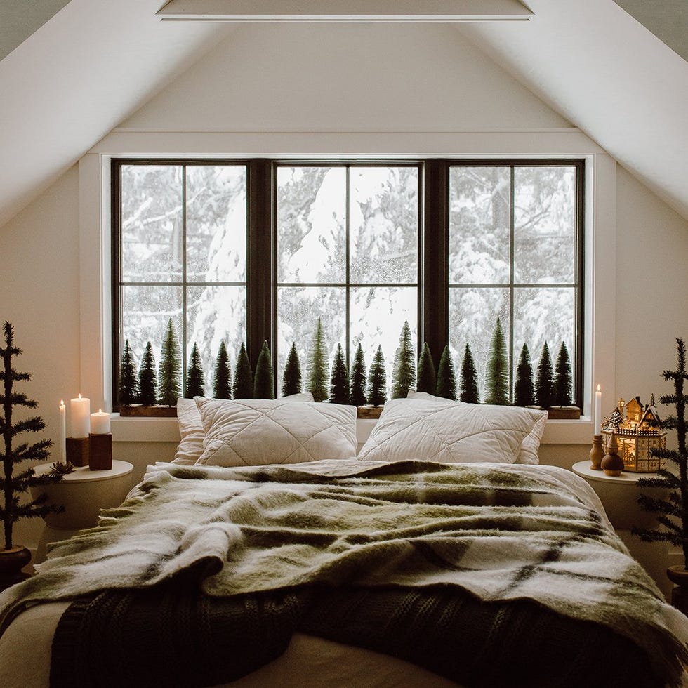 cozy bedroom with a winter view featuring a bed candles and decorative trees