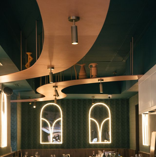 mesas llenas de cubiertos con paredes verdes decoradas con luces neón