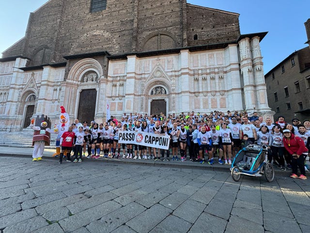 a group of runners standing in front of a historical building holding a banner
