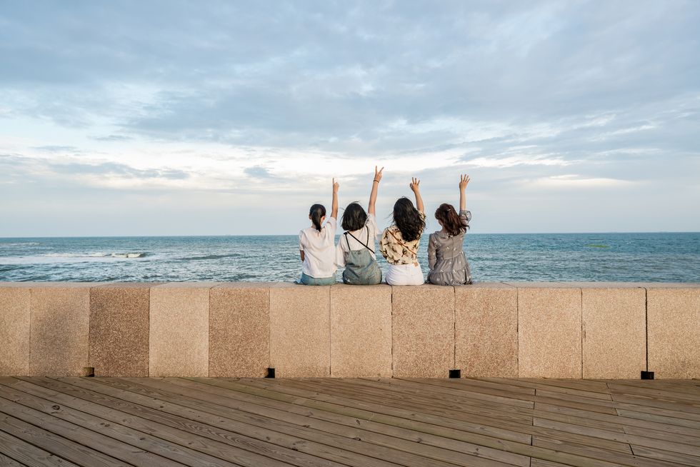 four beautiful girls sitting in front of the seaside, copy space
