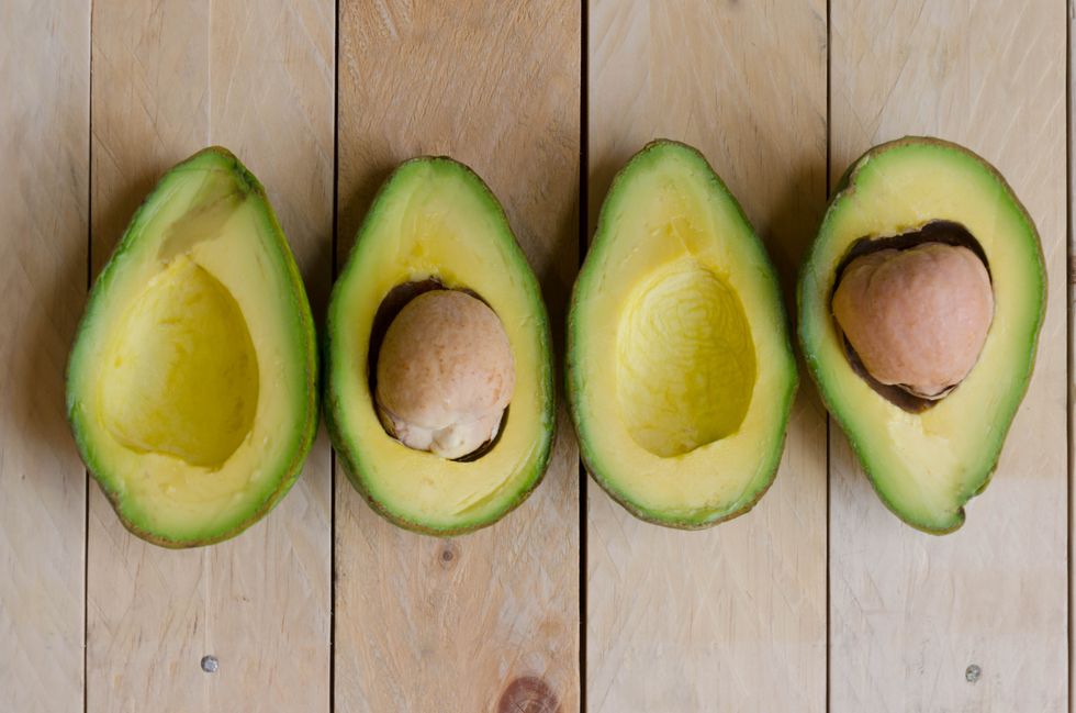 four halves of avocados on wood background