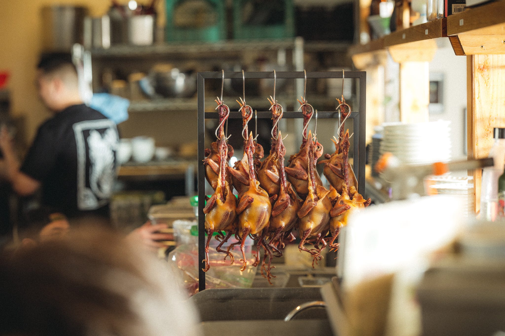 hanging roasted ducks in a kitchen setting