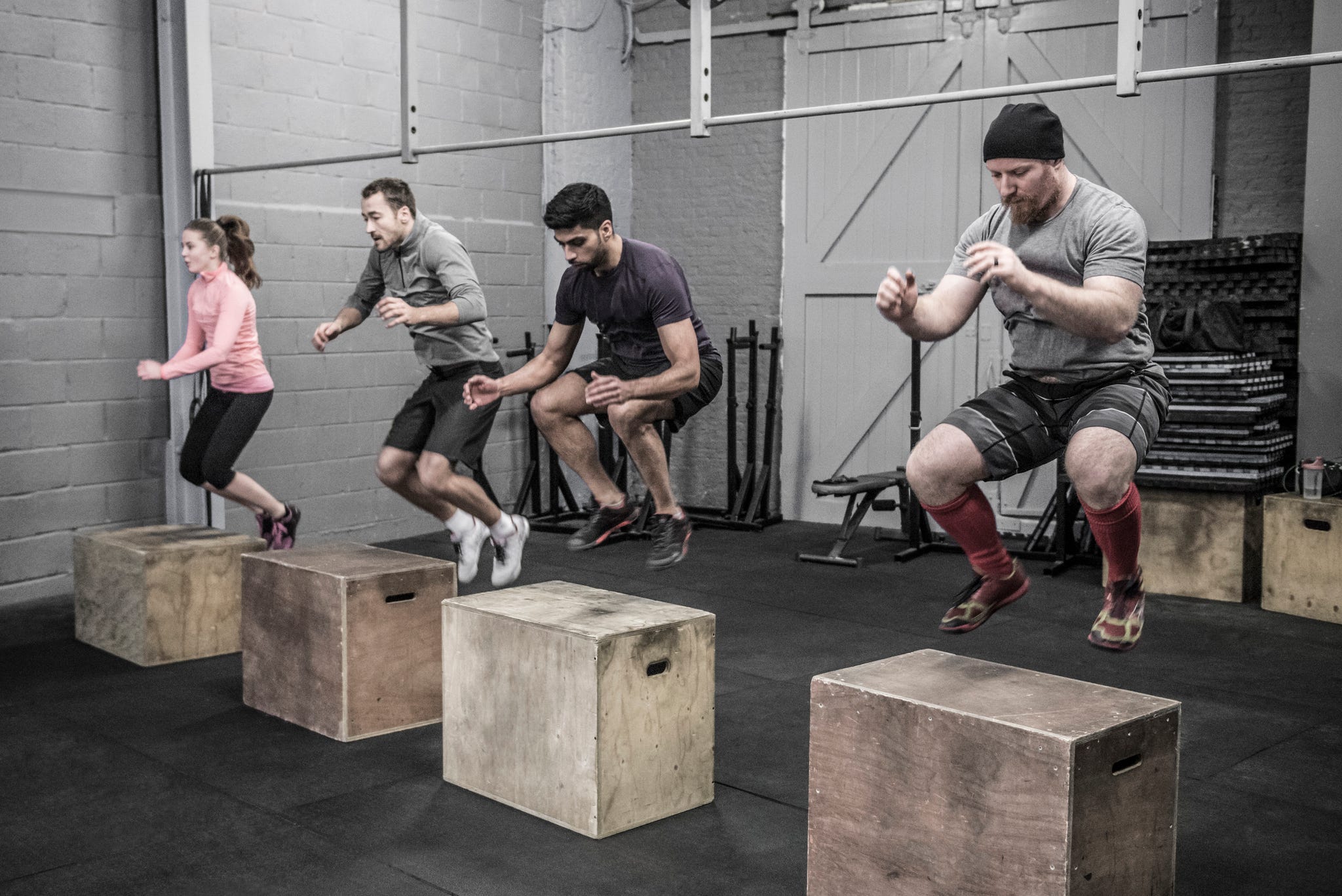 four people doing box jumps in cross training class