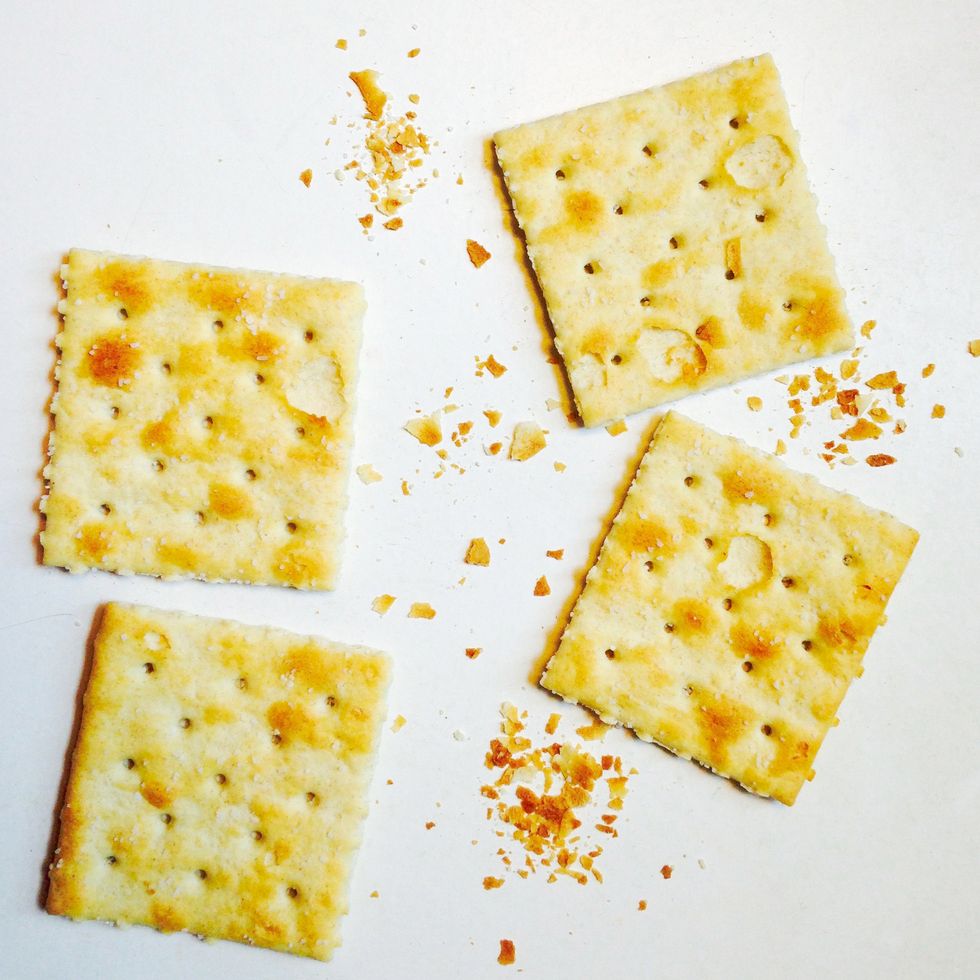 four saltine and crumbs on white