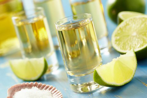 four tequila shots with lime and salt on a blue table