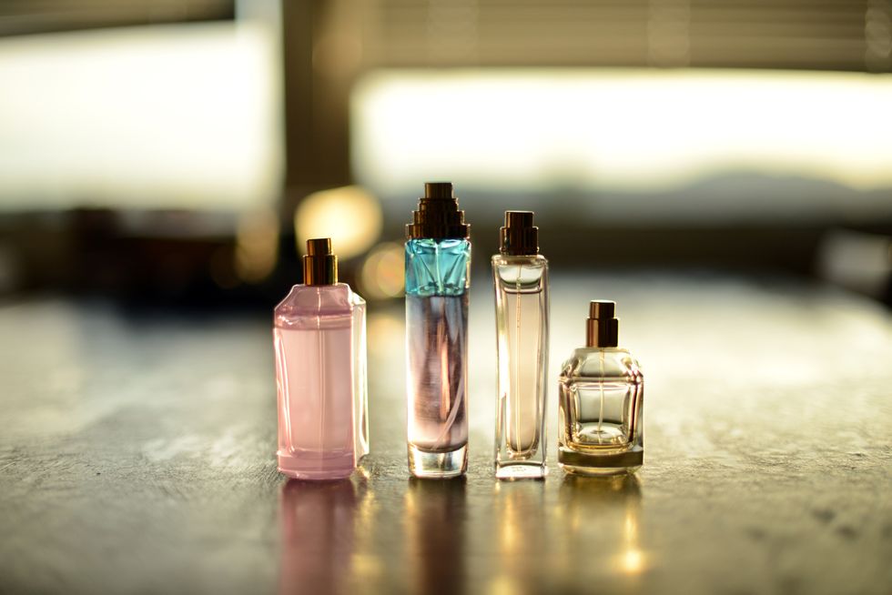 four transparent perfume bottles on a black table in a beautiful sunlight coming from two windows