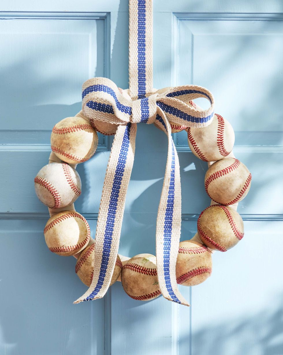 wreath made from vintage baseballs hanging on a blue door with a blue striped ribbon