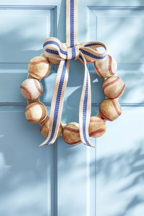 wreath made from vintage baseballs hanging on a blue door with a blue striped ribbon