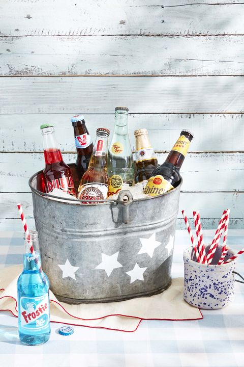 vintage galvanized metal bucket with white stars painted on it for 4th of july, filled with ice, beers and sodas